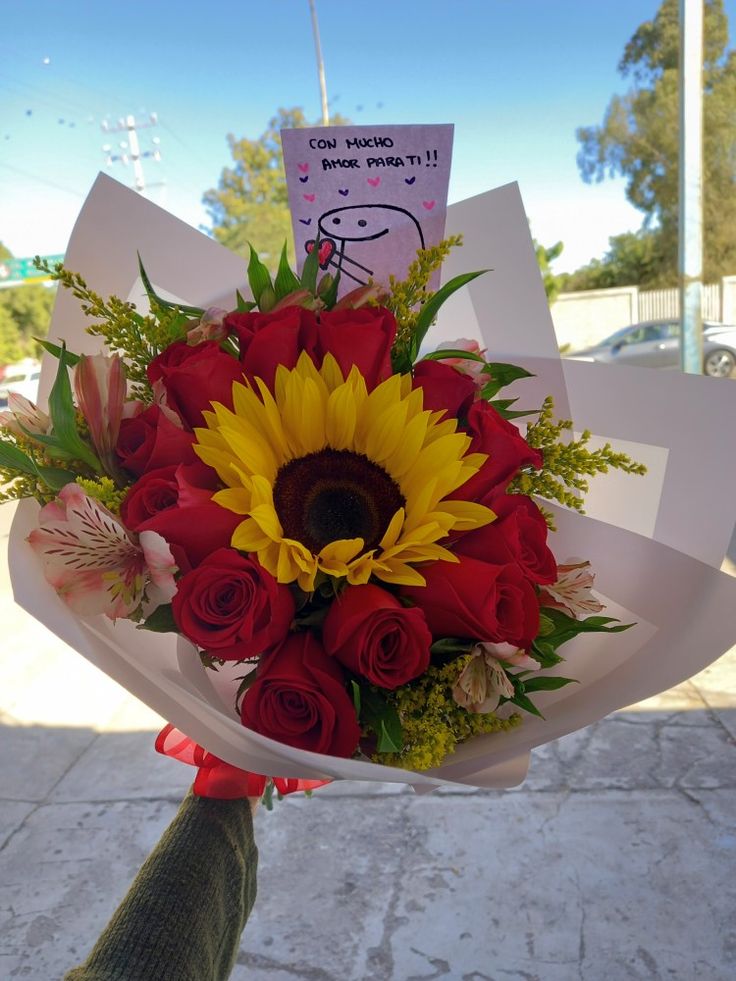 a person holding a bouquet of flowers with a sign on it that says i love you