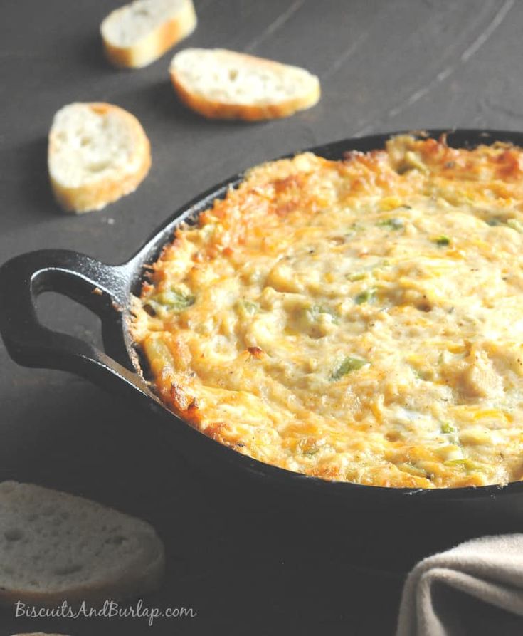 an omelet in a cast iron skillet on a table with slices of bread