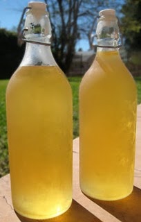 two glass bottles filled with liquid sitting on top of a wooden table