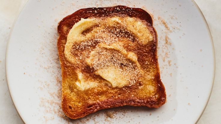 a piece of toast with powdered sugar on top sits on a plate, ready to be eaten