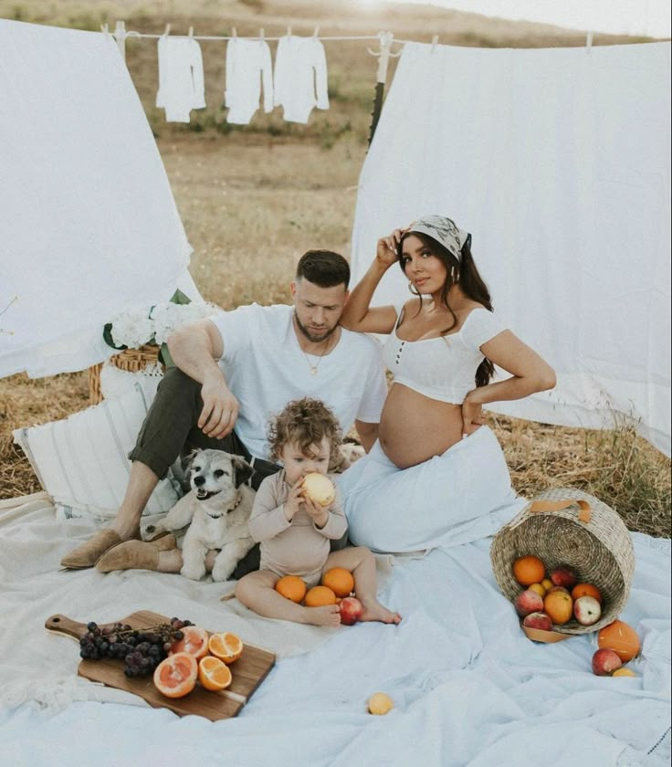 a man and woman sitting on a blanket with two dogs