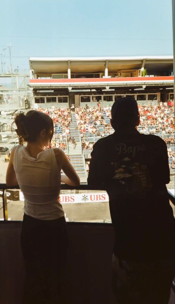 two people standing in front of an empty bleachers looking out at the crowd