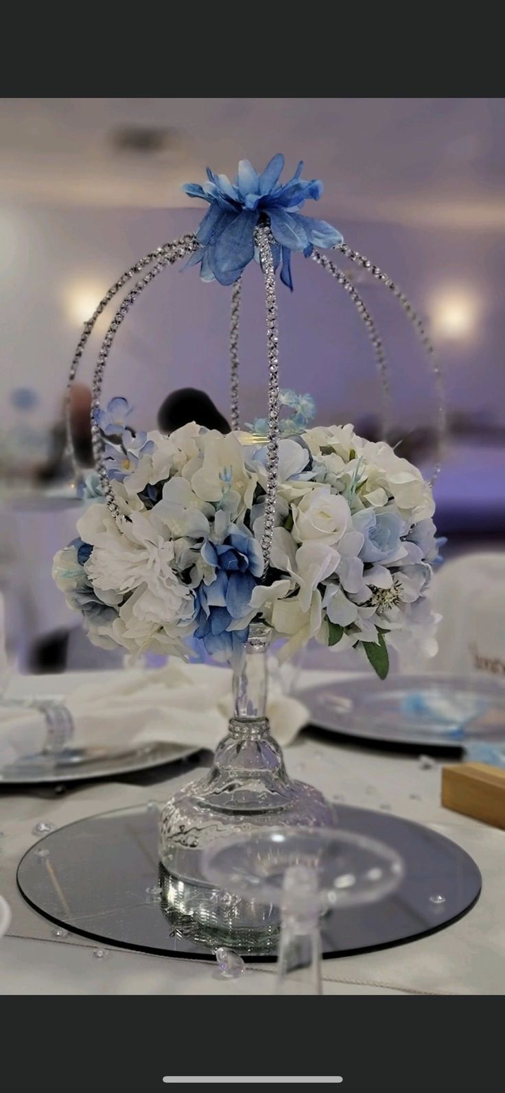 a centerpiece with blue and white flowers on a table