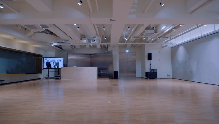 an empty room with wooden floors and large screen on the wall in front of it