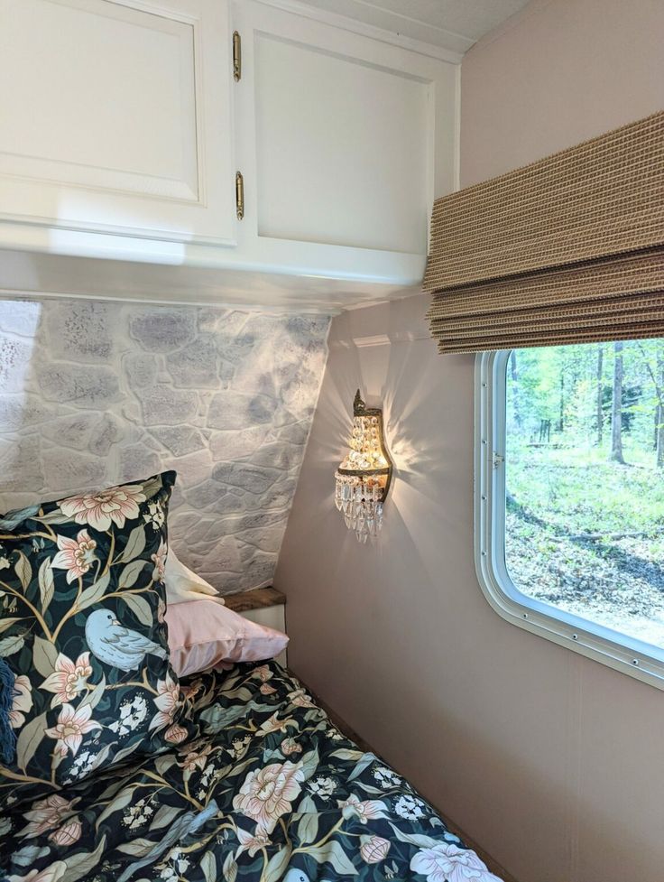 a bed in a bedroom next to a window with a lamp on the headboard