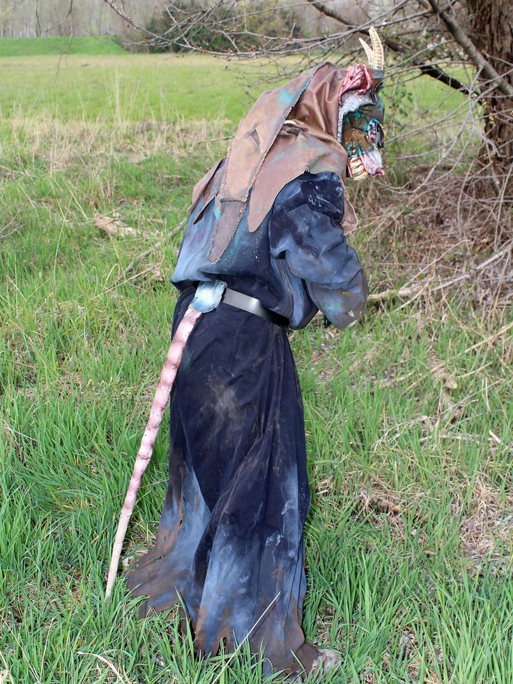 a statue is standing in the grass with a long stick on it's head