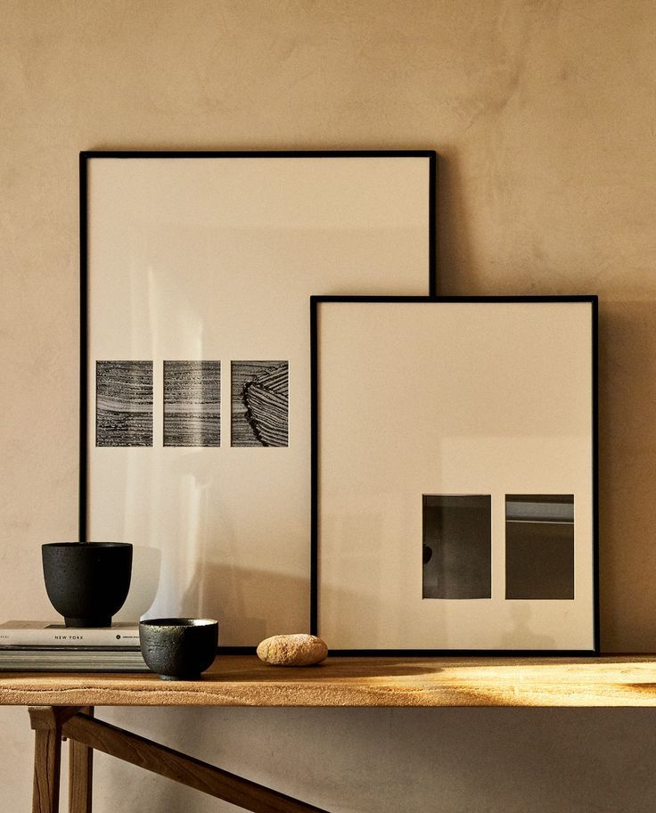 three framed photographs sit on a wooden table