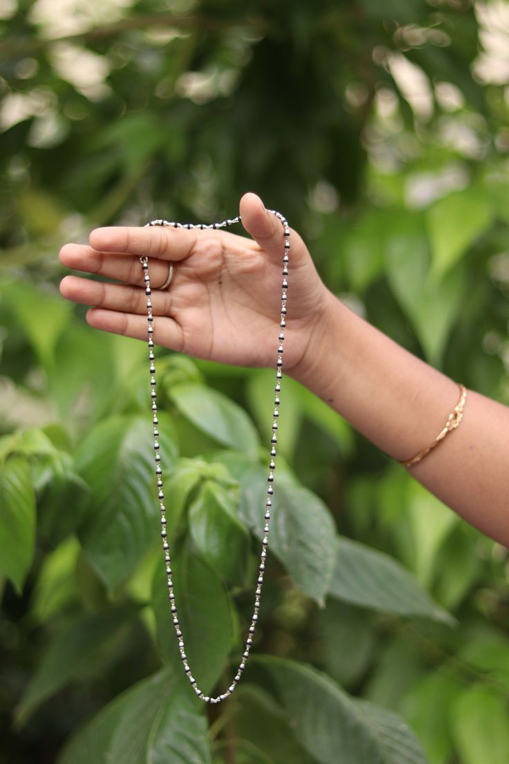 Introducing the exquisite Vrindavan Made One Round Tulsi Mala, a timeless piece of devotion and spirituality. Crafted with meticulous attention to detail, this sacred mala is a symbol of divine connection and inner peace. The Tulsi Mala features beads of rich black color, each carefully chosen for its high quality and purity. Made from the revered holy basil plant, also known as Tulsi, these beads carry a profound spiritual significance. Tulsi is considered a sacred herb in Hinduism and is believed to have immense healing properties, promoting tranquility and purifying the mind, body, and soul. To enhance the elegance and durability of each bead, they are delicately capped with shimmering silver. The silver caps not only add a touch of refinement but also protect the Tulsi beads, ensuring Handmade Silver Temple Necklace With Round Beads, Traditional Silver Mala As A Gift, Festive Silver Necklace With Beaded Chain, Silver Long Temple Necklace For Gift, Spiritual Necklaces For Puja With Polished Beads, Silver Beads Temple Necklace Gift, Silver Temple Jewelry Necklaces With Round Beads, Traditional Silver Mala As Gift, Silver Temple Jewelry Necklace With Round Beads