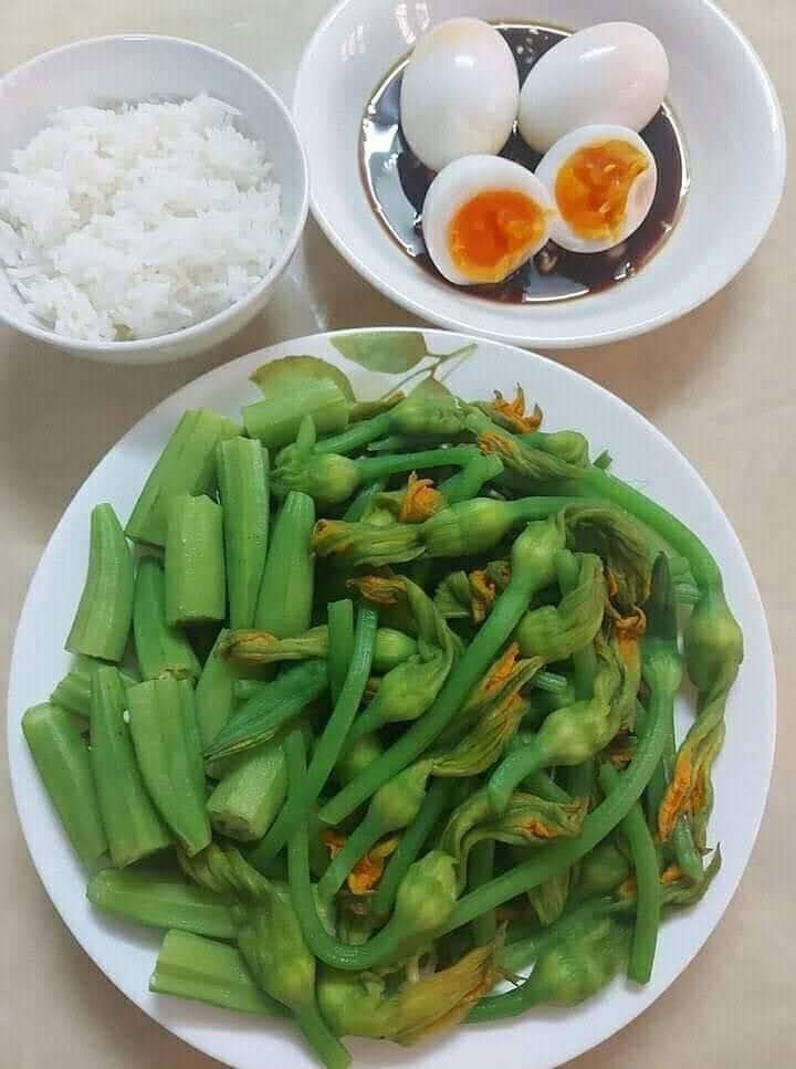 two plates filled with green beans and eggs on top of a table next to rice