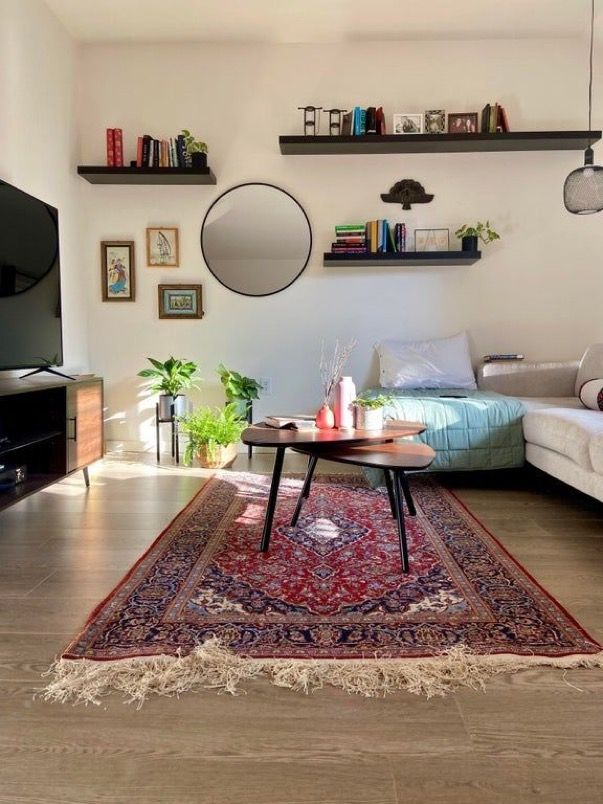 a living room filled with furniture and a large rug on top of a hard wood floor