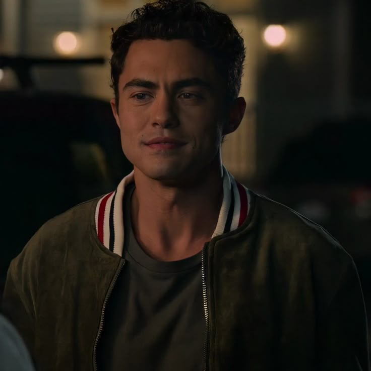 the young man is looking into the camera while standing in front of a building at night