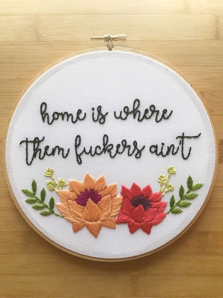 a white embroidery hoop with some flowers and the words home is where them flickers are