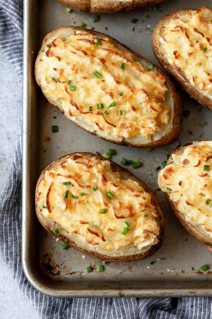 baked potatoes with cheese and chives on a baking sheet, ready to be eaten