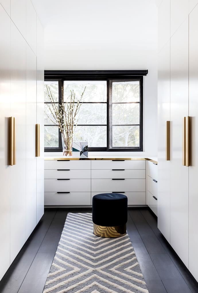 a kitchen with white cabinets and black counter tops next to a large window in the corner