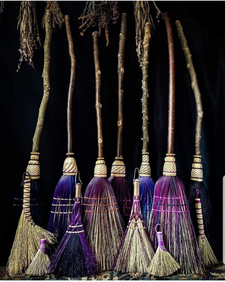 four brooms are lined up in front of some trees with purple and blue colors