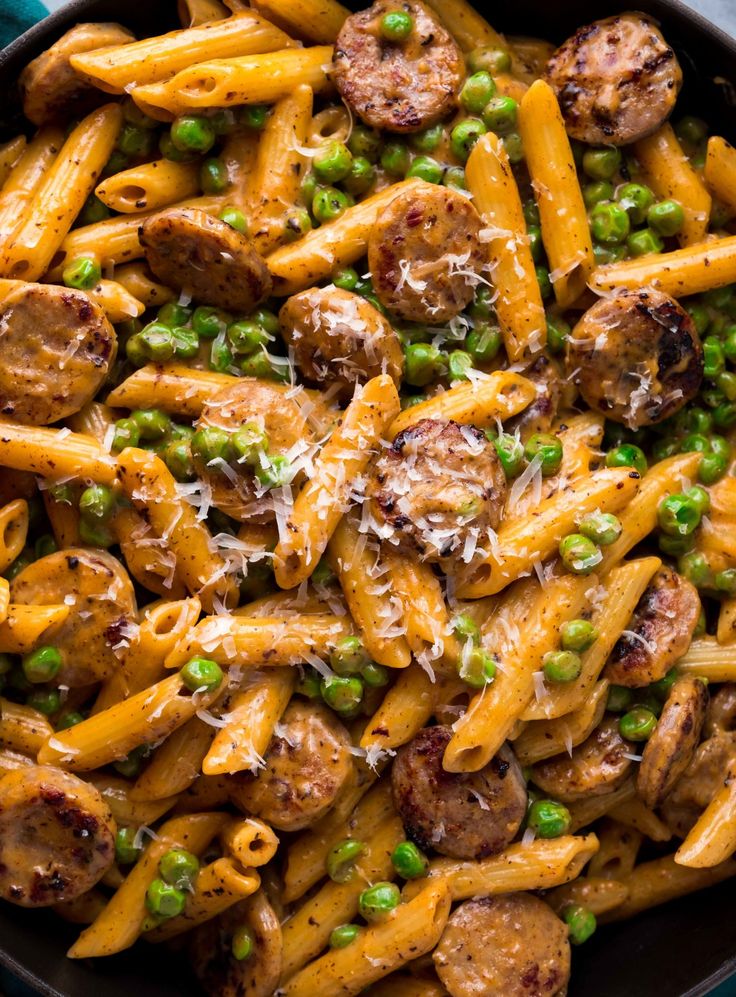 a skillet filled with pasta, peas and sausage