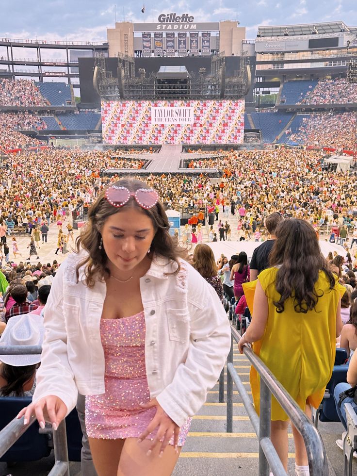 a woman in a short pink dress and white jacket at a stadium