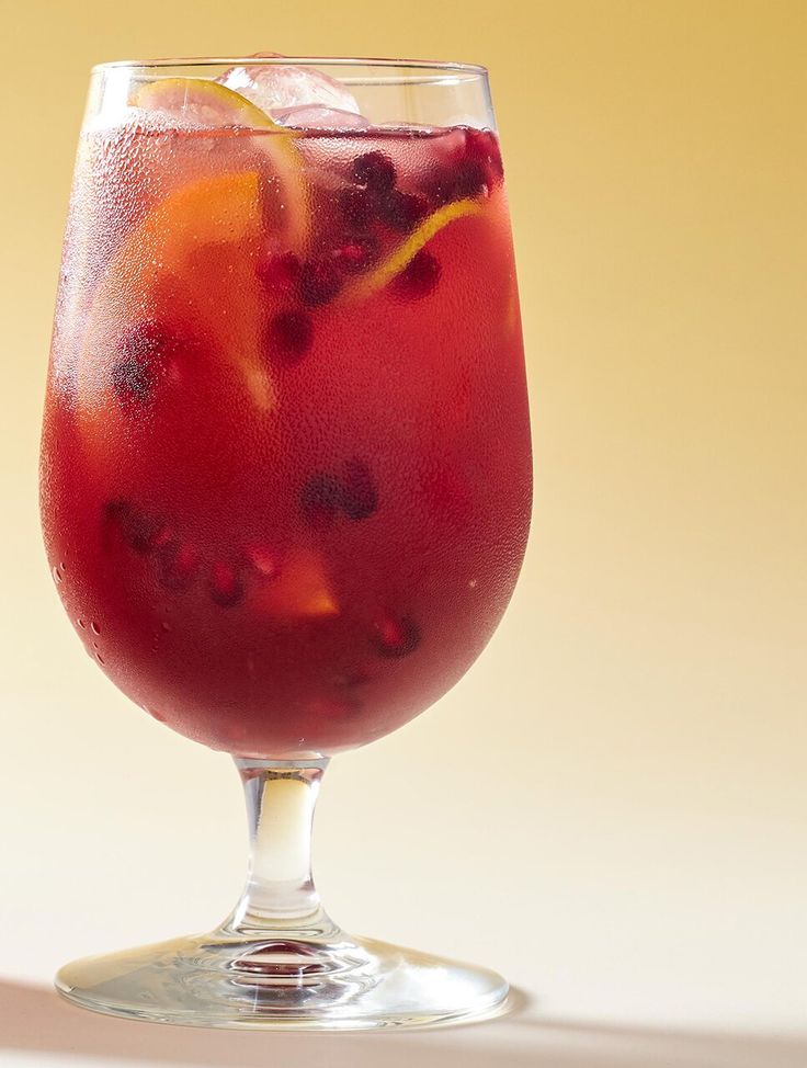 a glass filled with red liquid and garnished with orange slices on the rim