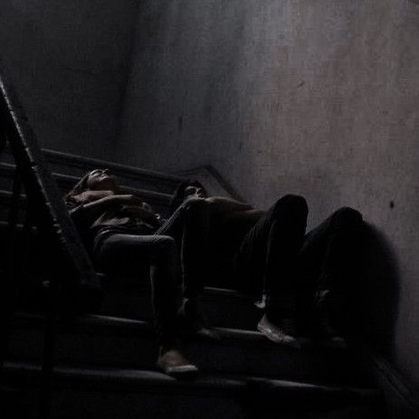 two people are sleeping on the stairs in an empty room with no one around them