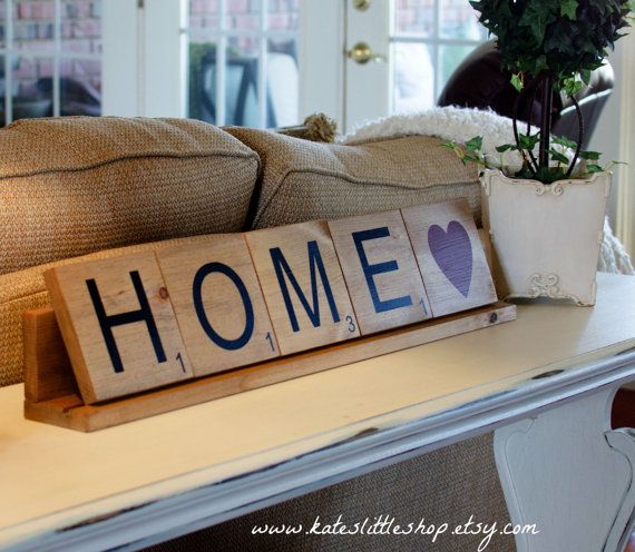 a wooden block with the word home on it sitting on a table next to a potted plant