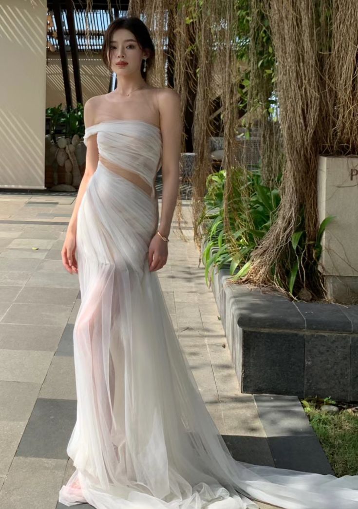 a woman in a white dress standing on the sidewalk