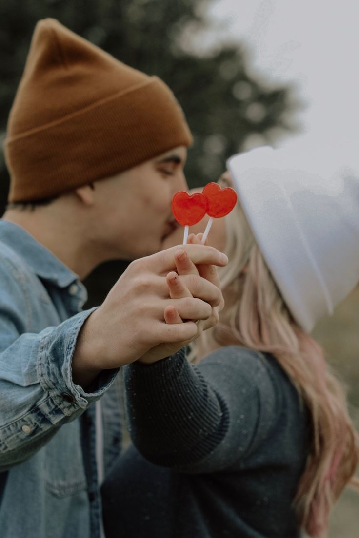 a man and woman kissing each other while holding lollipops in their hands