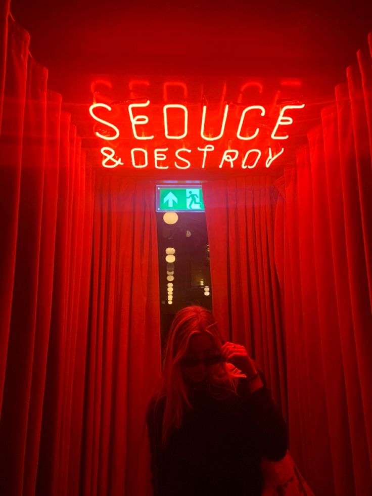 a woman standing in front of a red neon sign