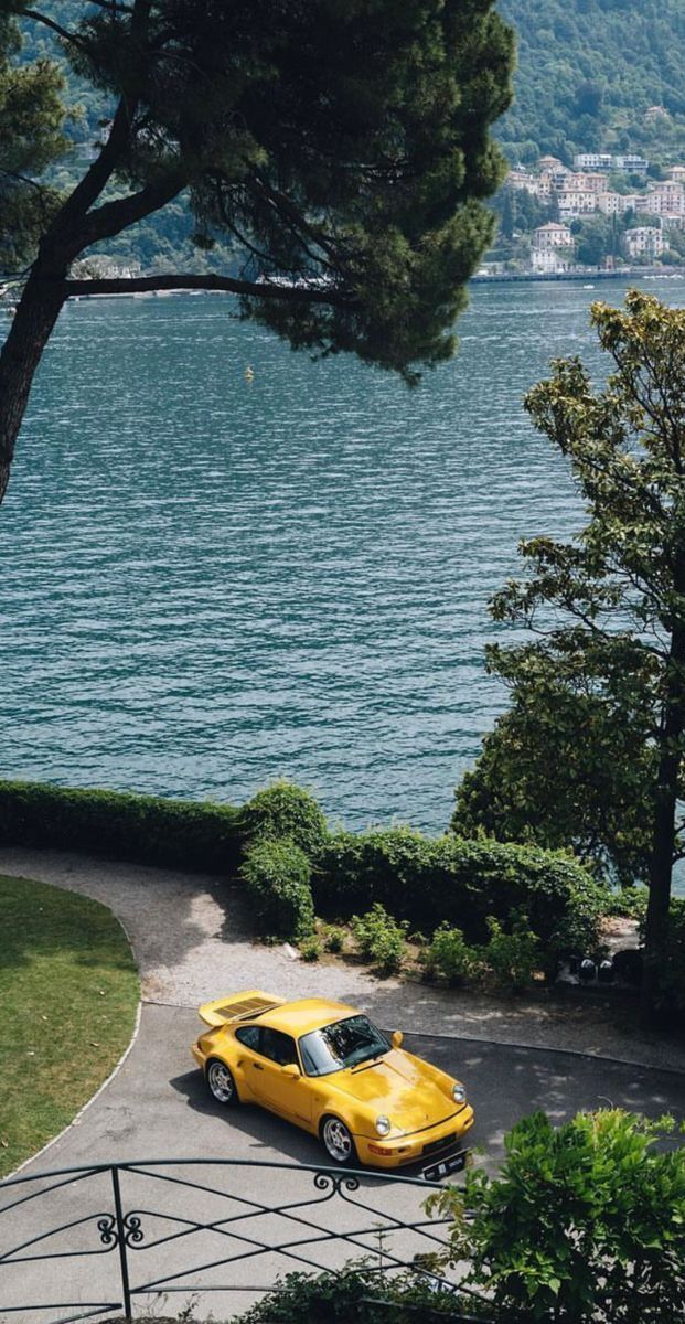 a yellow car parked on the side of a road next to a body of water