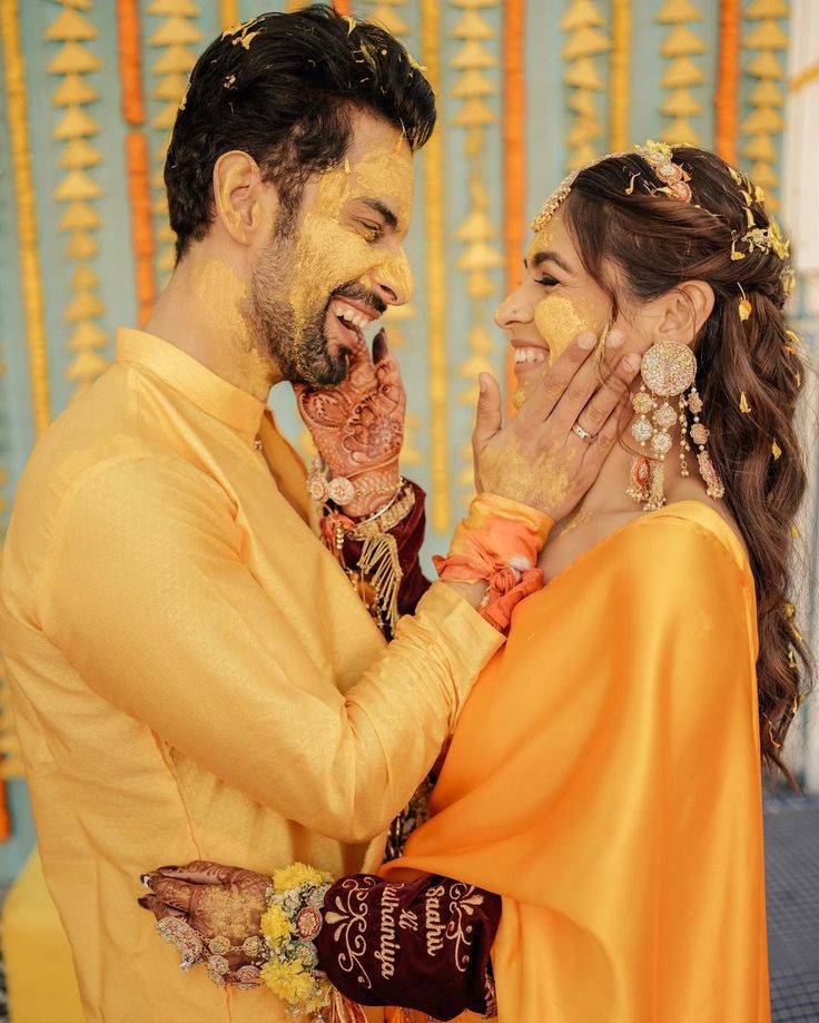 a man and woman dressed in yellow posing for the camera with their faces painted gold