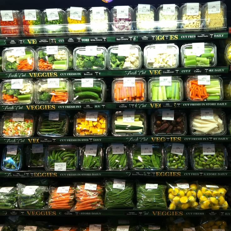 many different types of vegetables are displayed in plastic containers on the shelves at a grocery store