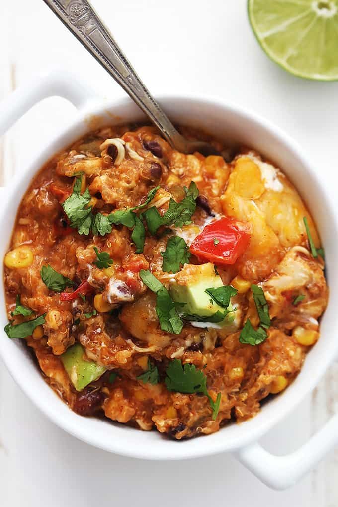 a close up of a bowl of food on a table with a spoon and lime