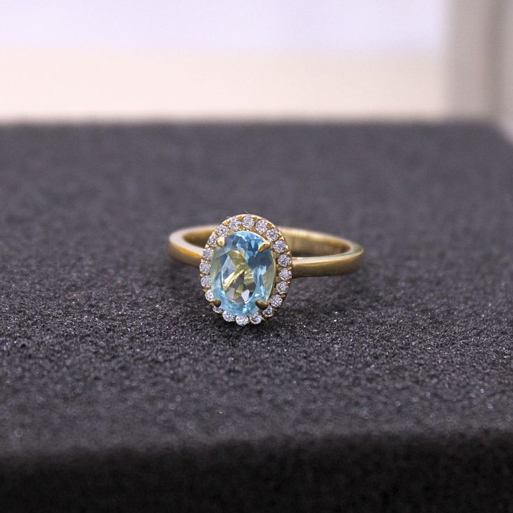 an oval blue topaz ring sits on a black surface with white and yellow diamonds