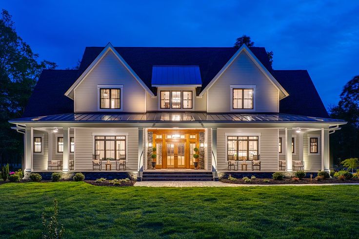 a large white house with lots of windows and lights on it's front porch