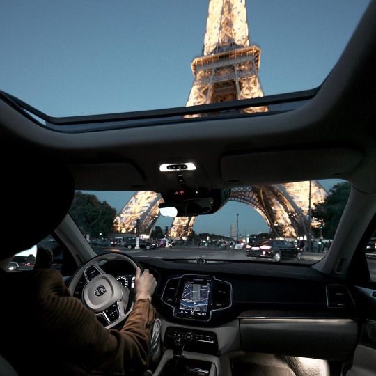 a person driving a car in front of the eiffel tower with a quote on it