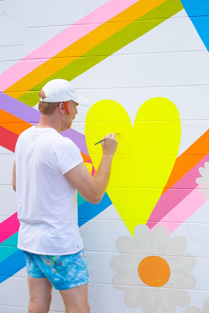 a man is painting a heart on the wall