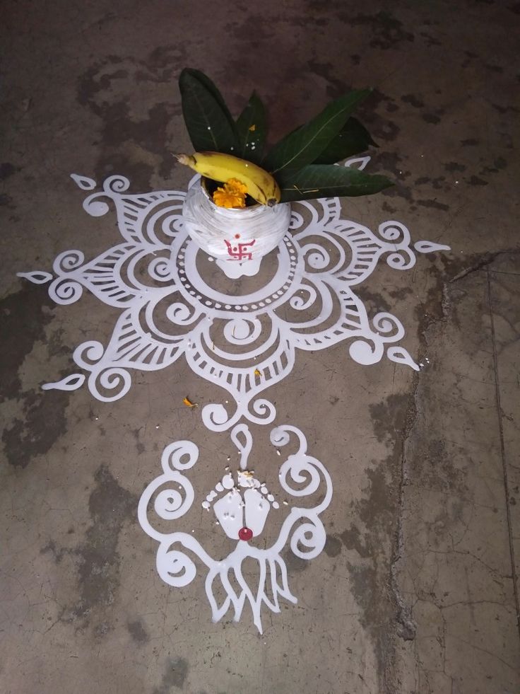 a potted plant sitting on top of a cement floor next to a white painted design