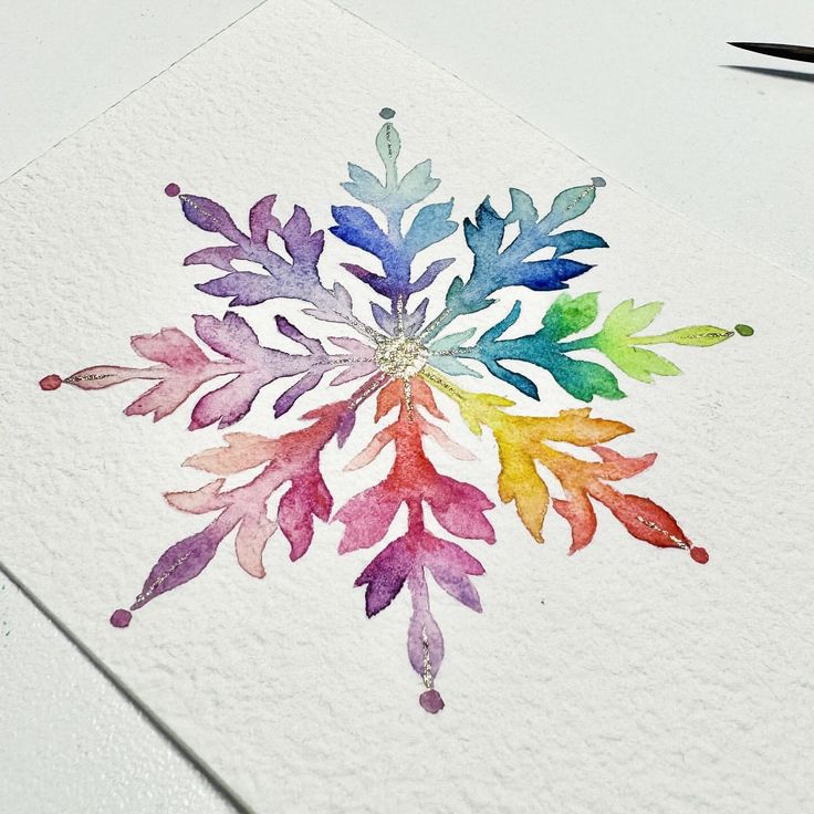 a watercolor snowflake is shown on a piece of paper