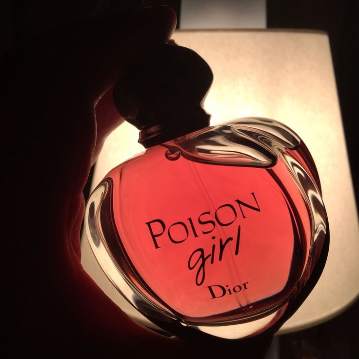 a person holding a bottle of perfume in front of a table lamp that says, poson girl dior