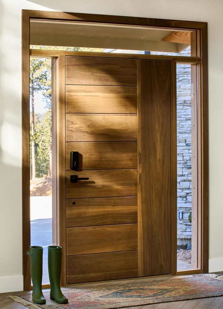 a pair of green rubber boots sitting in front of a wooden door with glass panels