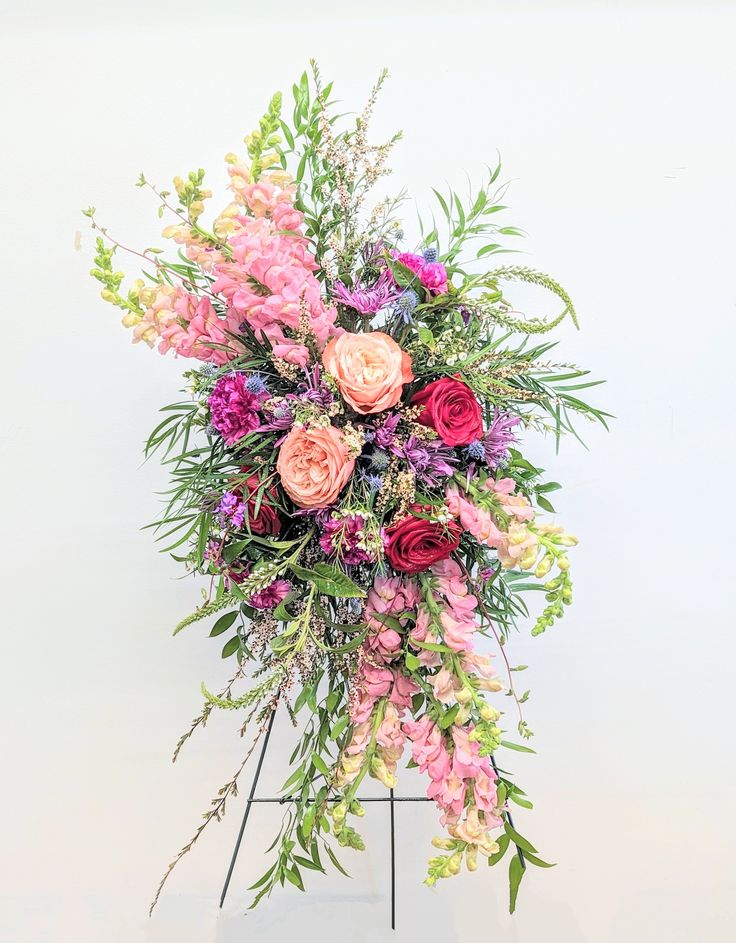 an arrangement of flowers is displayed on a stand