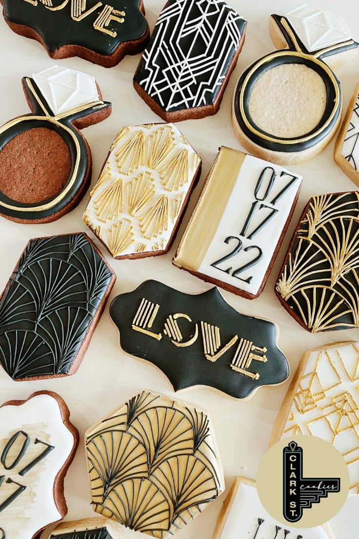 cookies decorated with black and gold designs on a white table top, including the number twenty five