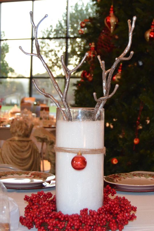 a vase with some branches in it sitting on a table next to a christmas tree