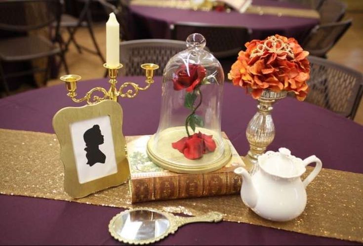 a table topped with a vase filled with flowers next to a book and a candle