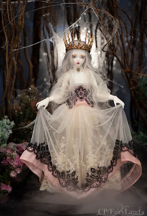 a doll dressed in white and black with a crown