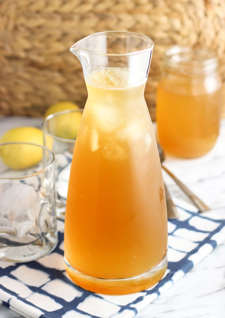 a pitcher of lemonade sitting on top of a table next to glasses and a basket