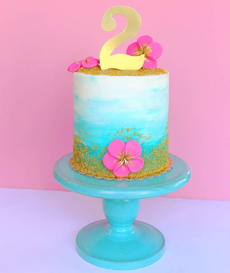 there is a blue cake with pink flowers on the bottom and gold numbers on top