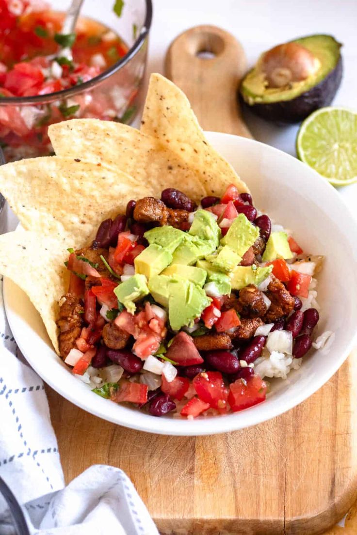 a white bowl filled with black beans, guacamole and tortilla chips