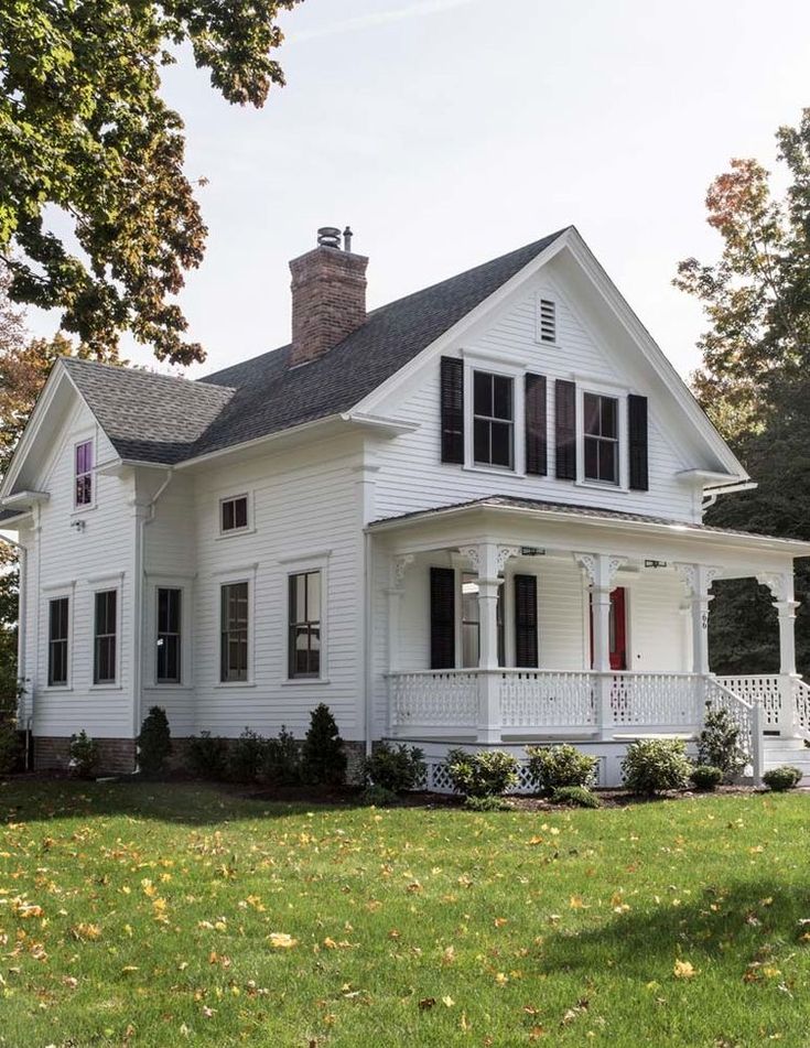 a white house with red shutters on the front porch and two storyed windows