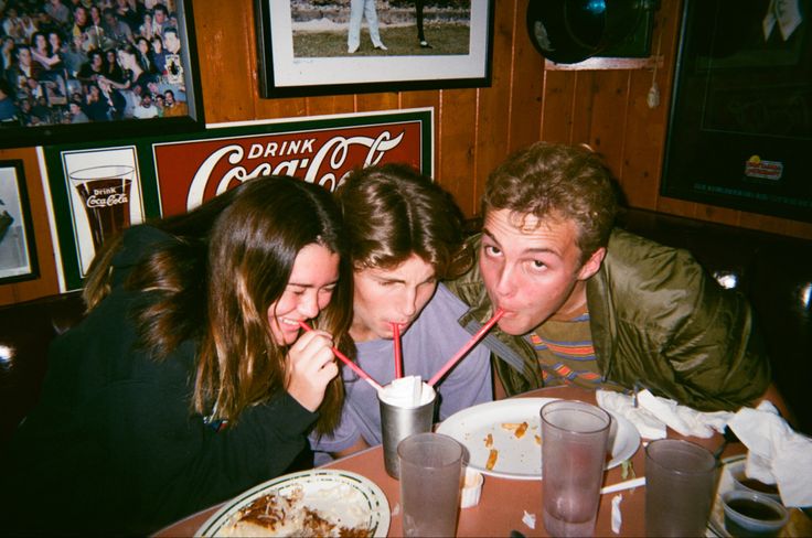 three people sitting at a table with drinks in front of them