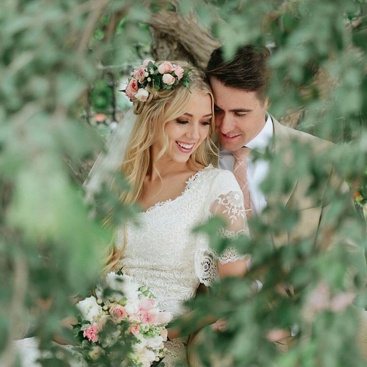 a bride and groom standing in the woods